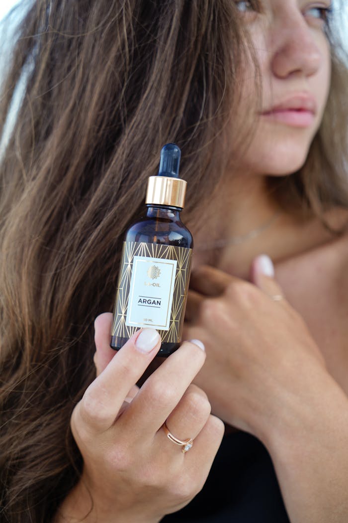 Woman with long hair holding a luxurious argan oil bottle. Ideal for beauty and skincare promotions.
